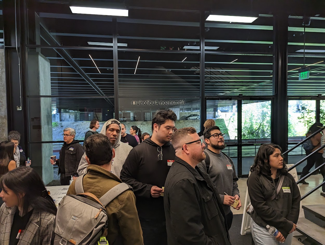 A group of people standing in a building and looking out of frame.